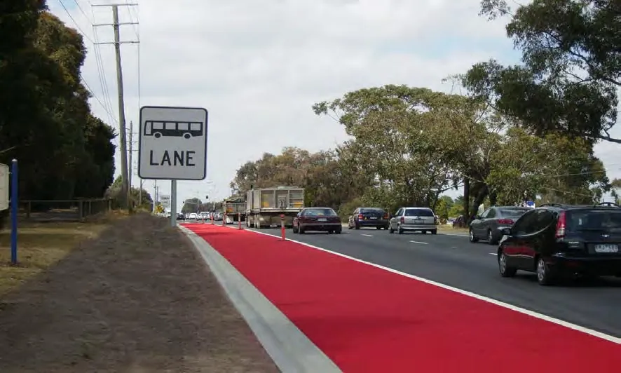 Red bus lane beside a main road